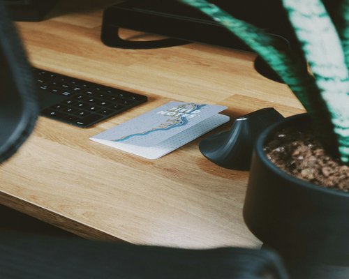 A glass of water and a notepad beside a digital tablet on a modern wooden desk